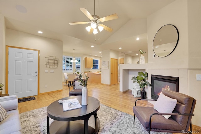 living room featuring lofted ceiling, a fireplace, light hardwood / wood-style floors, and ceiling fan