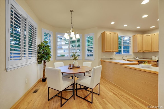 dining space featuring an inviting chandelier, sink, and light hardwood / wood-style floors