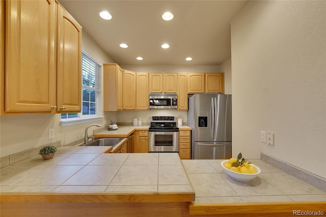 kitchen featuring sink, tile countertops, light brown cabinets, appliances with stainless steel finishes, and kitchen peninsula