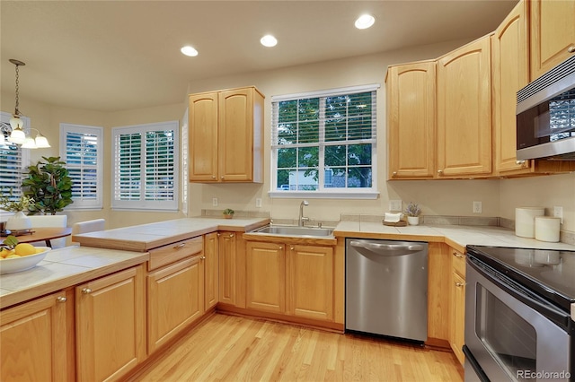 kitchen featuring light brown cabinetry, sink, appliances with stainless steel finishes, tile counters, and pendant lighting