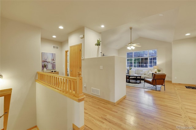 hallway with vaulted ceiling and light wood-type flooring