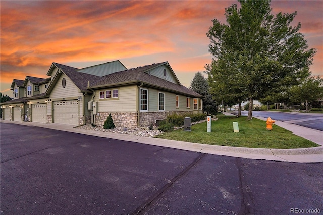 property exterior at dusk featuring a garage and a lawn