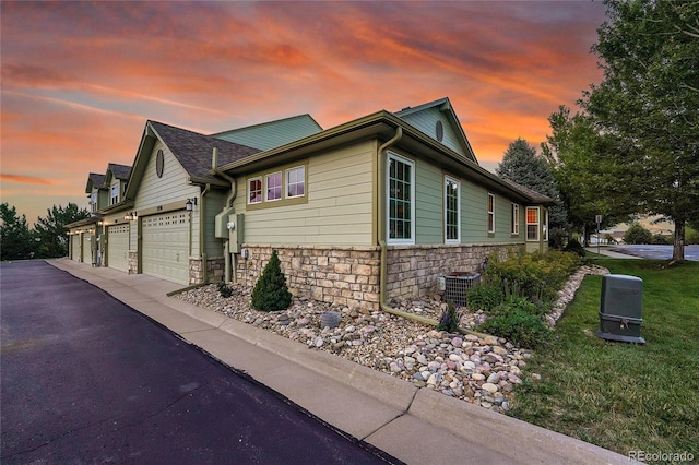 property exterior at dusk with a garage and central AC