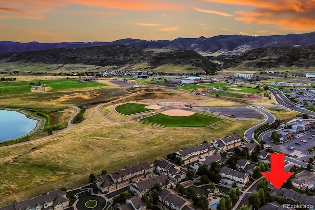 aerial view at dusk featuring a water and mountain view