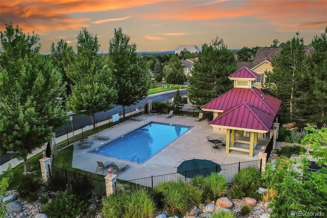 pool at dusk featuring a gazebo and a patio area