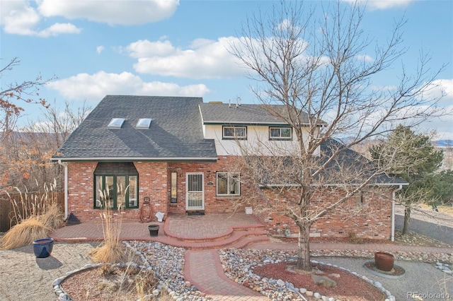 view of front of property with brick siding, a patio, and roof with shingles