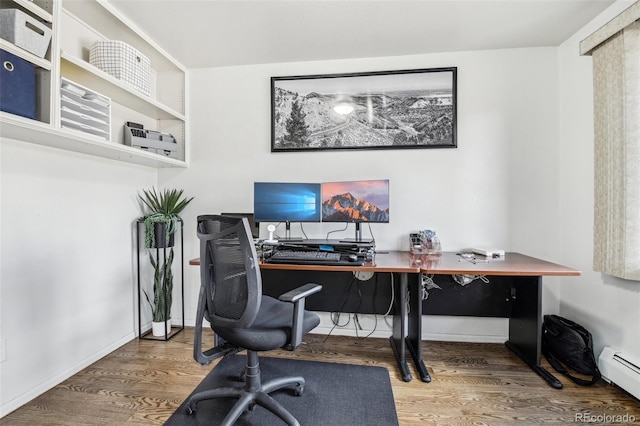 office space featuring baseboards, a baseboard heating unit, and wood finished floors