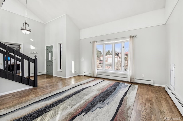 foyer entrance featuring a baseboard radiator, stairs, baseboards, and wood finished floors