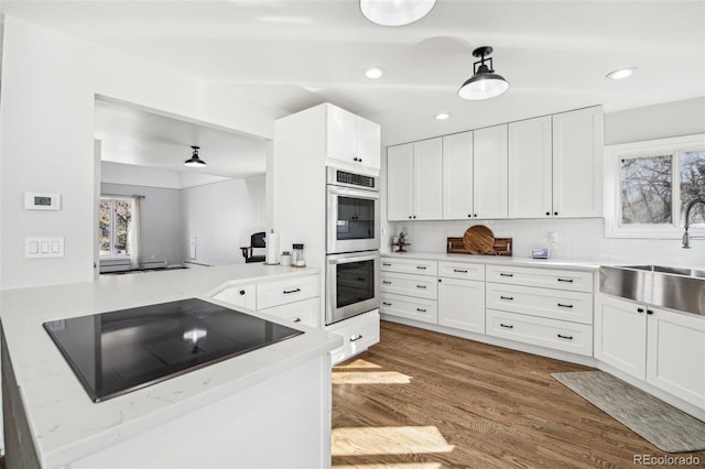 kitchen with stainless steel double oven, plenty of natural light, a sink, and black electric cooktop