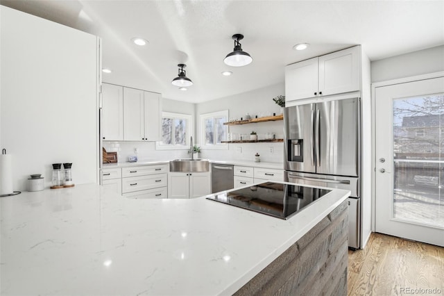 kitchen featuring appliances with stainless steel finishes, a sink, light stone counters, and white cabinets