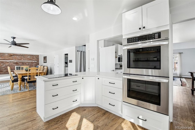 kitchen with light countertops, stainless steel double oven, light wood-style flooring, and white cabinets