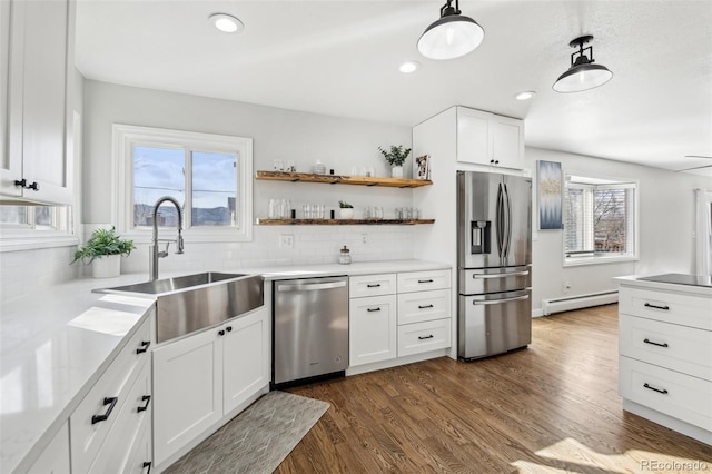 kitchen featuring a baseboard heating unit, a sink, white cabinets, appliances with stainless steel finishes, and dark wood finished floors