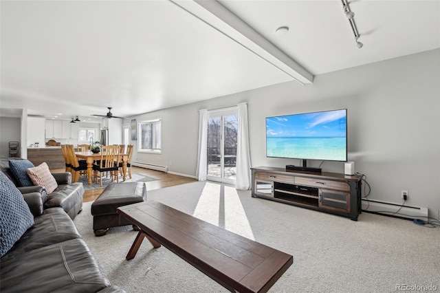 living area with baseboards, rail lighting, beamed ceiling, and baseboard heating