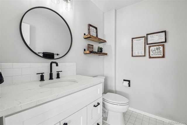 half bath featuring tasteful backsplash, toilet, vanity, tile patterned flooring, and baseboards