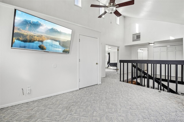 interior space featuring carpet, visible vents, a ceiling fan, high vaulted ceiling, and baseboards