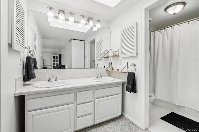 bathroom featuring double vanity, baseboards, toilet, and a sink