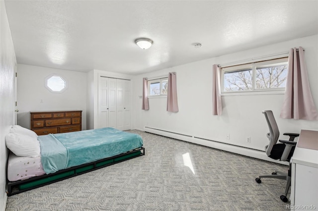 carpeted bedroom featuring a textured ceiling, a closet, and baseboard heating