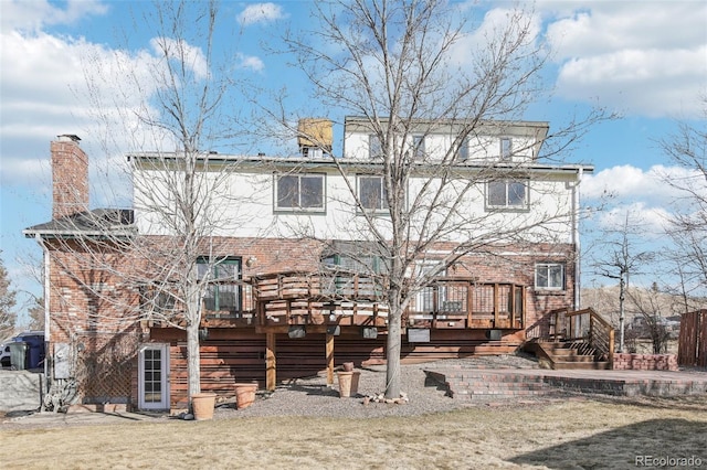 back of property featuring a chimney, brick siding, and a deck