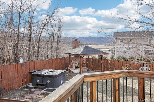 deck featuring a fenced backyard, a mountain view, and a hot tub