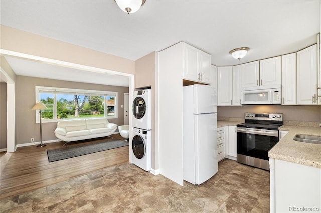 5142 S Pennsylvania St, Littleton, CO 80121 - kitchen with white appliances, stacked washer and clothes dryer, baseboards, open floor plan, and white cabinets