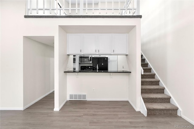 1732 S Trenton Unit 9, Denver, CO 80231 - kitchen with stainless steel microwave, refrigerator, wood finished floors, dark countertops, and white cabinets