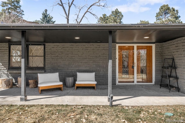 view of exterior entry with brick siding and a patio area