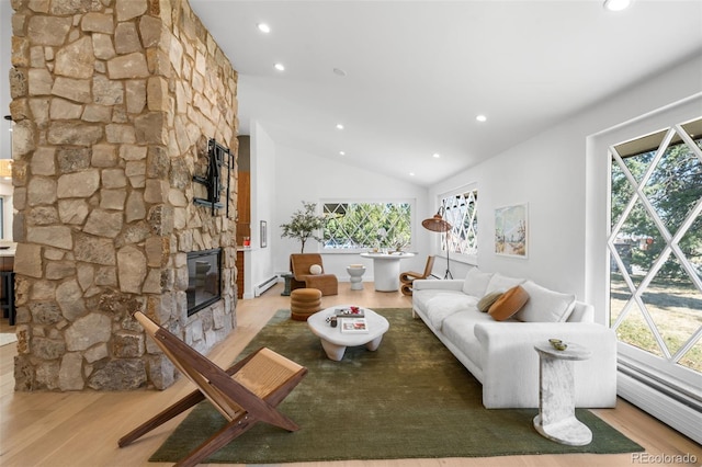 living area featuring light wood-type flooring, a wealth of natural light, baseboard heating, a fireplace, and a baseboard radiator