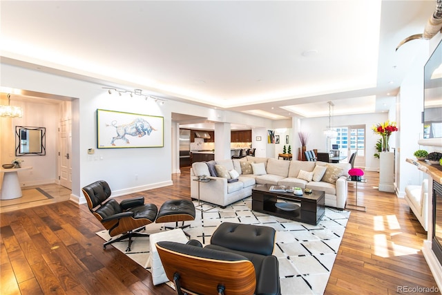 living room with a tray ceiling, hardwood / wood-style flooring, and a chandelier