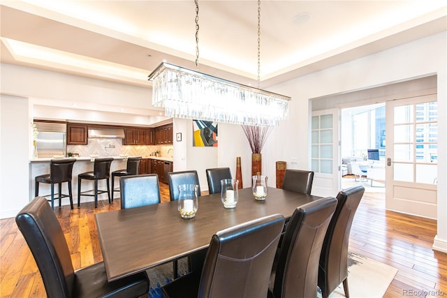 dining space with a tray ceiling and light hardwood / wood-style flooring