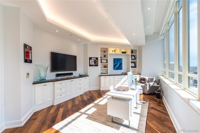 living room featuring hardwood / wood-style flooring, built in features, and a tray ceiling