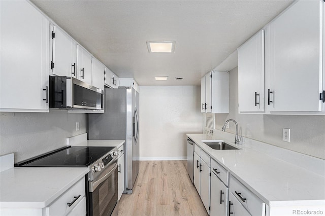 kitchen with white cabinets, a textured ceiling, sink, light wood-type flooring, and appliances with stainless steel finishes