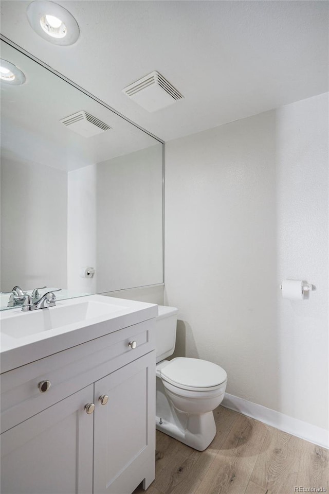 bathroom featuring wood-type flooring, toilet, and vanity