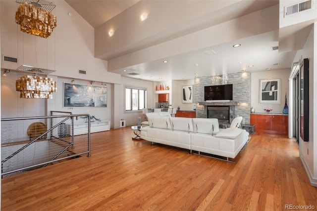 180 N Cook St Unit 509, Denver, CO 80206 - living area featuring light wood-type flooring, a chandelier, a stone fireplace, and a towering ceiling