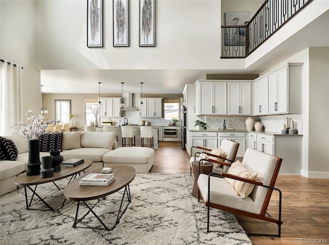 living room featuring a towering ceiling, wood-type flooring, and a healthy amount of sunlight