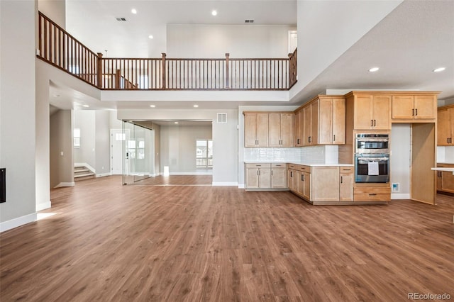 kitchen with stainless steel double oven, open floor plan, light countertops, and wood finished floors