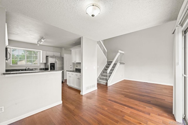 10349 W Fair Ave Unit A, Littleton, CO 80127 - kitchen featuring a textured ceiling, appliances with stainless steel finishes, dark countertops, dark wood-style floors, and white cabinets