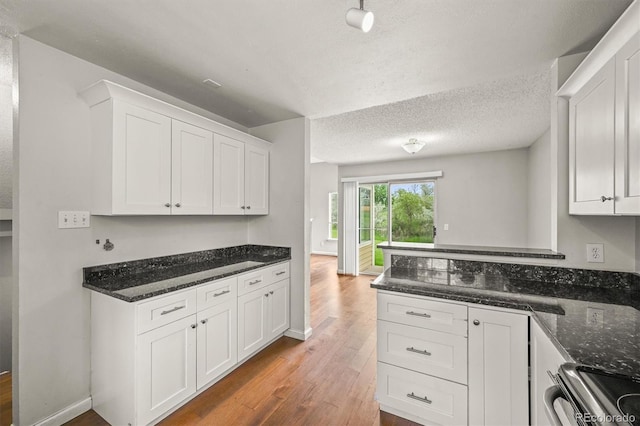 10349 W Fair Ave Unit A, Littleton, CO 80127 - kitchen with wood finished floors, white cabinetry, dark stone counters, stainless steel range, and a textured ceiling