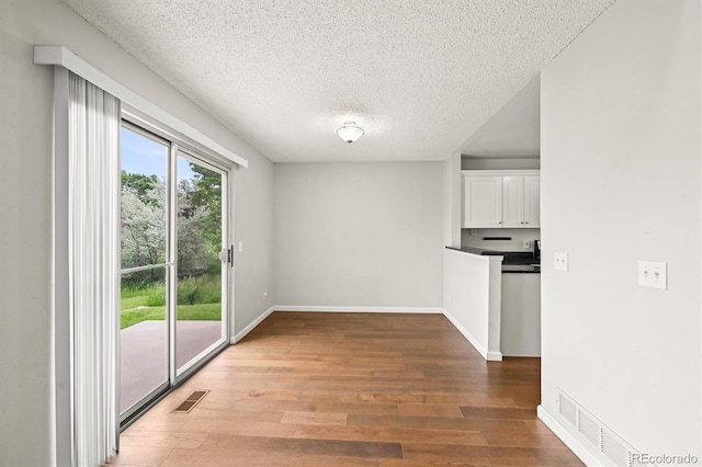 10349 W Fair Ave Unit A, Littleton, CO 80127 - unfurnished dining area with light wood finished floors, a textured ceiling, and baseboards