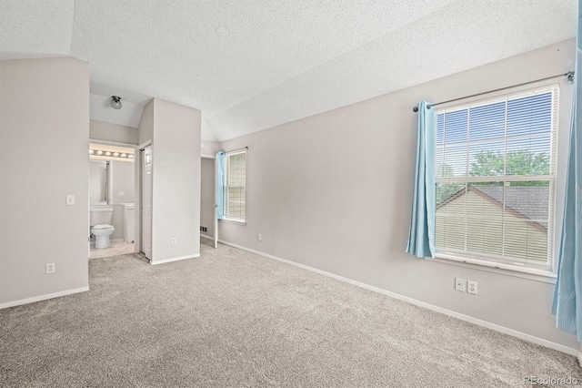 10349 W Fair Ave Unit A, Littleton, CO 80127 - unfurnished bedroom with carpet flooring, baseboards, a textured ceiling, connected bathroom, and vaulted ceiling