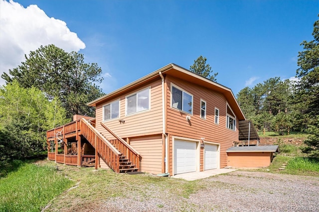 7284 Willa Ln, Evergreen, CO 80439 - back of property featuring stairway, gravel driveway, a deck, and an attached garage