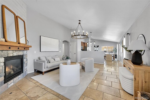 3838 Brush Rd, Castle Rock, CO 80108 - living area featuring vaulted ceiling, arched walkways, stone tile floors, a stone fireplace, and a chandelier