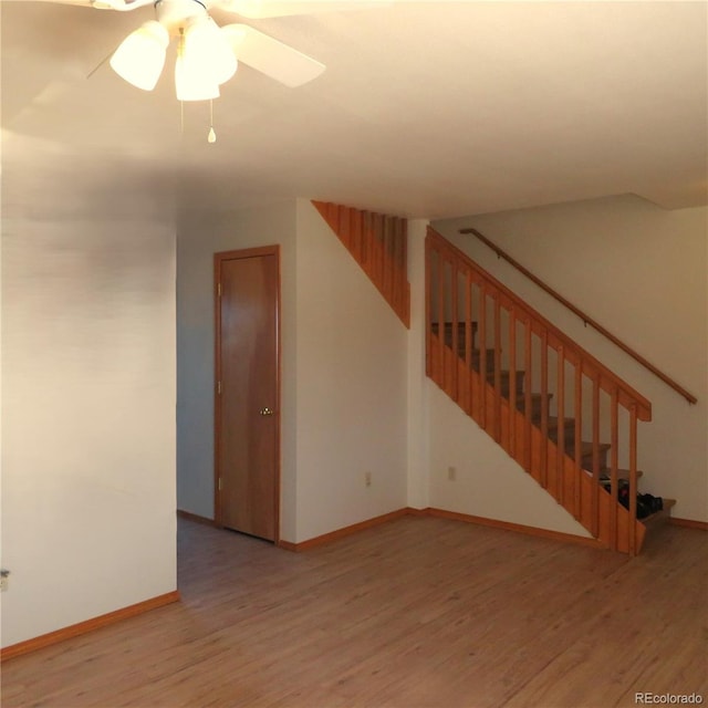 interior space featuring a ceiling fan, wood finished floors, baseboards, and stairs