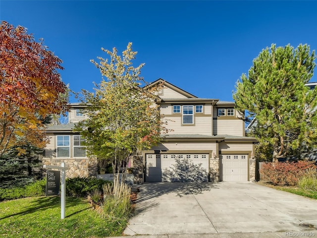 13075 Tamarac St, Thornton, CO 80602 - view of front of home featuring stone siding, an attached garage, and driveway