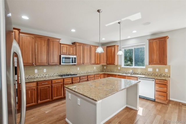 13075 Tamarac St, Thornton, CO 80602 - kitchen with appliances with stainless steel finishes, brown cabinets, light wood-style flooring, a kitchen island, and a sink
