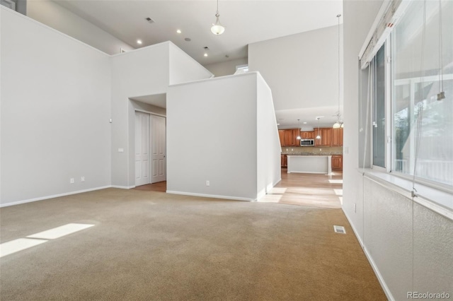 13075 Tamarac St, Thornton, CO 80602 - unfurnished living room featuring light carpet, a high ceiling, recessed lighting, and baseboards