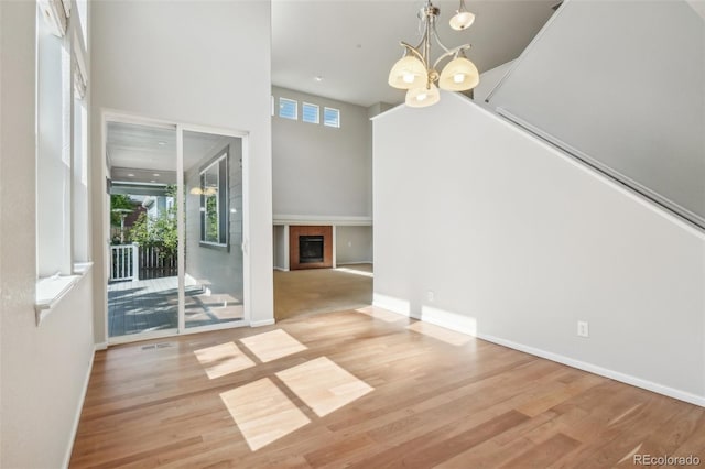 13075 Tamarac St, Thornton, CO 80602 - unfurnished dining area with wood finished floors, a glass covered fireplace, a chandelier, a towering ceiling, and baseboards