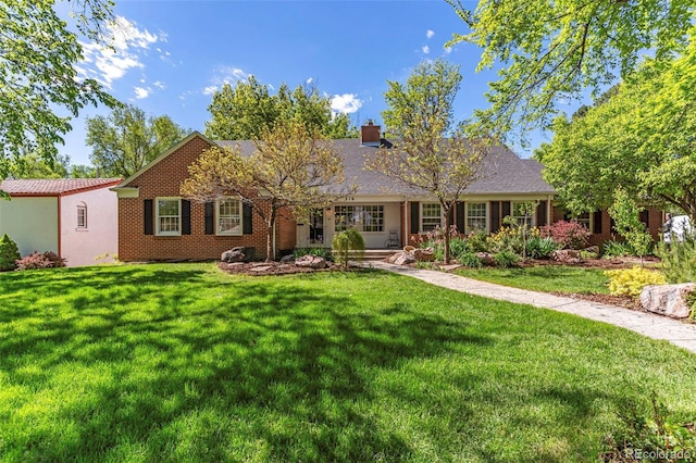 ranch-style home with brick siding, a chimney, and a front yard