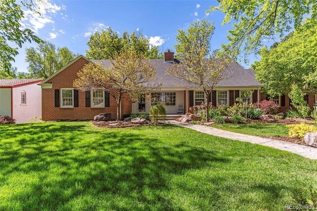 ranch-style house featuring brick siding, a chimney, and a front lawn