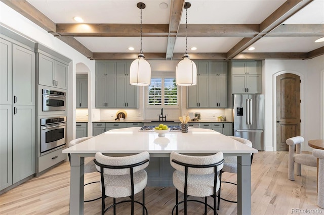 852 Pontiac St, Denver, CO 80220 - kitchen featuring appliances with stainless steel finishes, gray cabinets, light wood finished floors, a kitchen bar, and beam ceiling