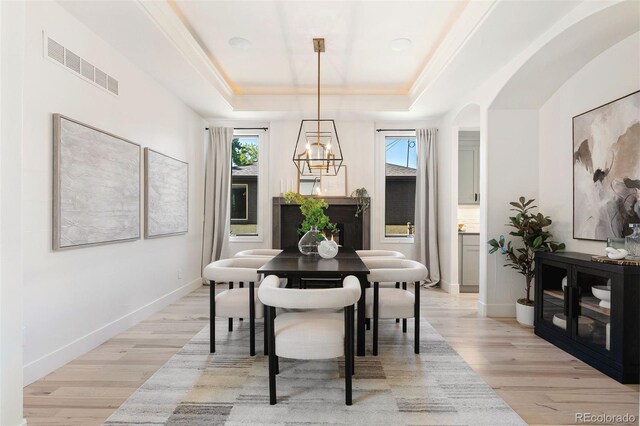 852 Pontiac St, Denver, CO 80220 - dining area with a tray ceiling, light wood-style floors, a chandelier, and arched walkways